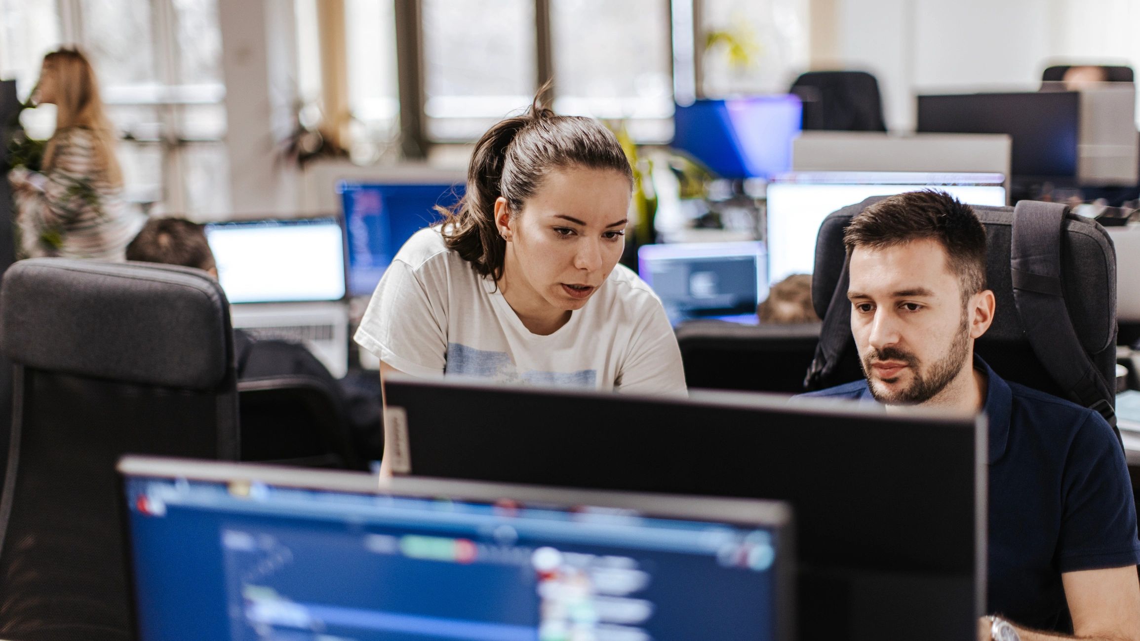 Two developers collaborating at a computer in an office