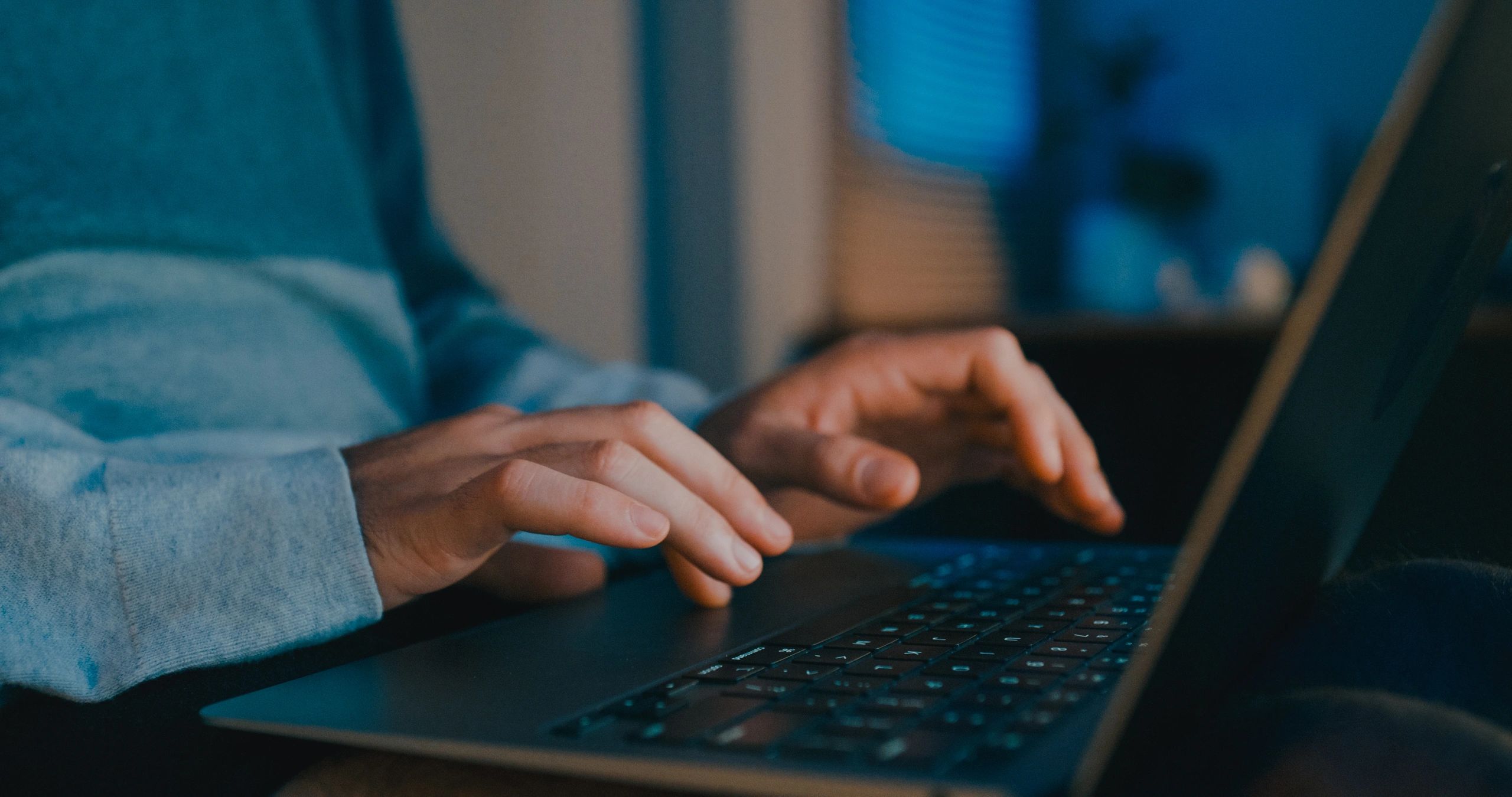 Close-up of hands typing on a laptop while coding